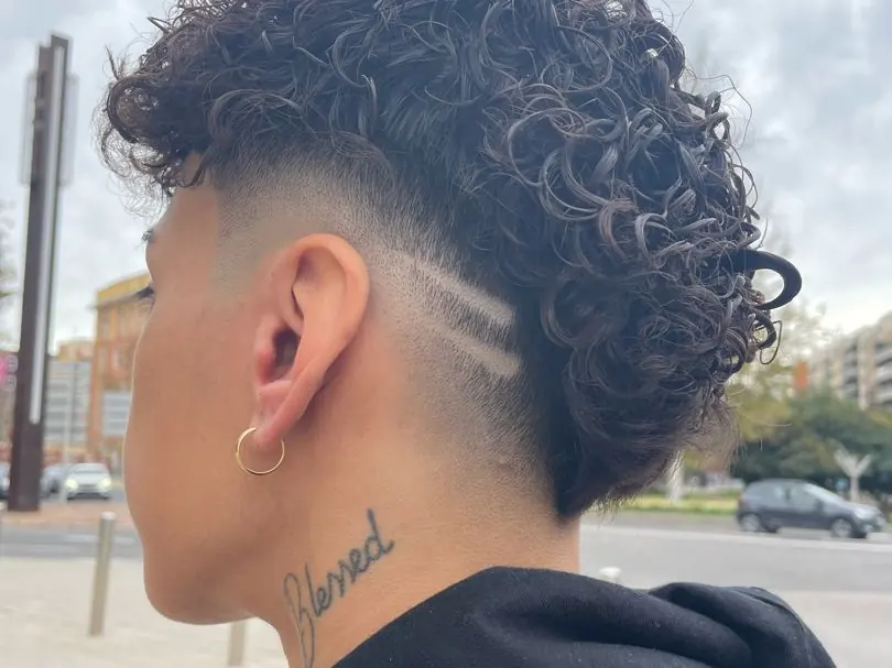 Degradado con línea rapada lateral sobre pelo rizado
